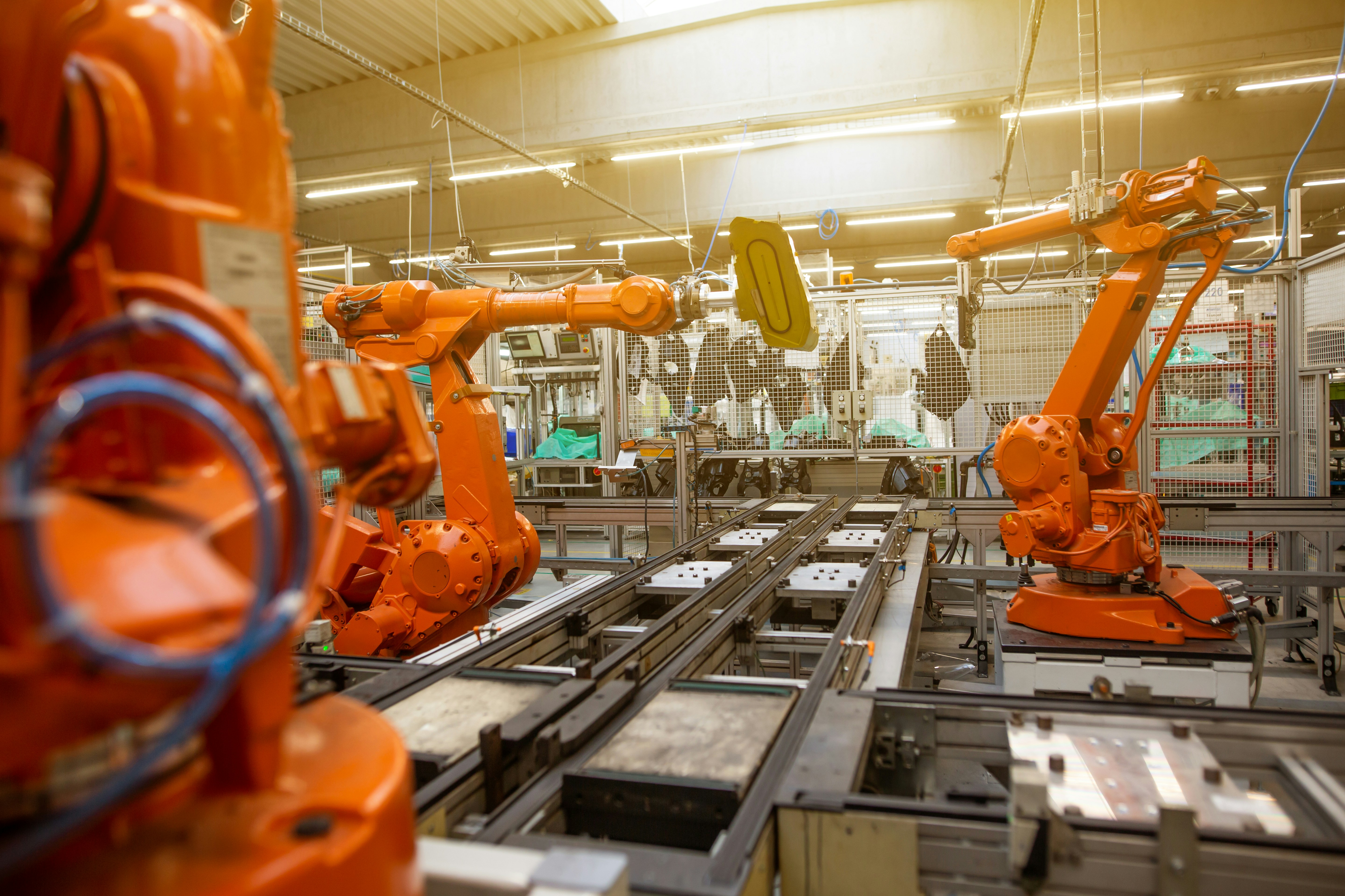 Industrial space with orange robotic arms and manufacturing equipment